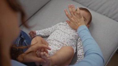 Anne küçük kızıyla oturma odasında kanepede oynuyor sevgi ve özenle evde güçlü bir aile bağı yaratıyor.