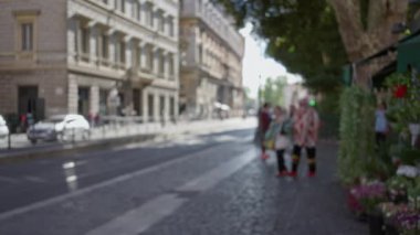 Roma, İtalya 'da bir cadde boyunca yürüyen kadın ve erkeğin bulanık manzarası. Tarihi binalar ve şehir atmosferinin bokeh etkisi altında olması..