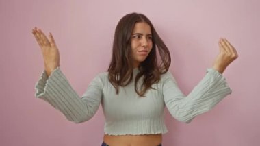 Pembe arka planda el kol hareketi yapan, sıradan esmer saçlı bir kadın.