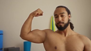 Kapalı alanda kaslarını esneten sakallı ve kendine güvenen bir adam. Güç ve zindelik gösteriyor..