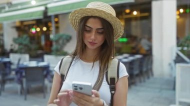 Şapka takan kadın şehir dışındaki kafede modern yaşam tarzı ve bağlantısını gösteren akıllı telefon kullanıyor..