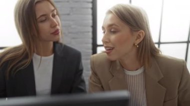 Bir ofis ortamında konuşan kadınlar, iş arkadaşları ya da iş arkadaşları olarak görülen, modern bir iş ortamında profesyonel bir tartışma ve etkileşim anı paylaşıyorlar..