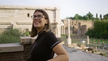Roma, İtalya 'daki Roma forumunda gülümseyen bir kadın. Arka planda antik harabeler ve yemyeşil yeşillikler var. Avrupa' da bir sevinç anı ve tarihi keşif anı yakalıyor..