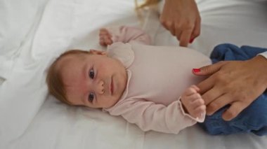 Bebek kadın elleriyle yatakta uzanıyor. Yatak odası ortamında çocuğa bakıyor. Aile sıcaklığını ve sevgisini samimi bir evde yakalıyor.. 