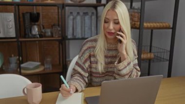 Oturma odasında dizüstü bilgisayar kullanan bir kadın defterde yazarken telefonla konuşuyor..