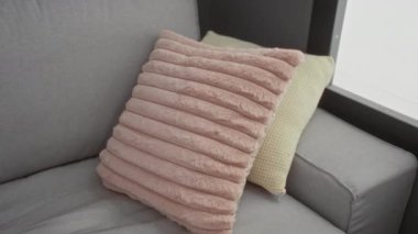 Genç bir kadın kanepede dinleniyor. Kapalı bir odada pembe bir yastığa sarılıyor.