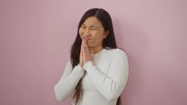 Bir kadın, pembe arka planda ellerini birleştirip 