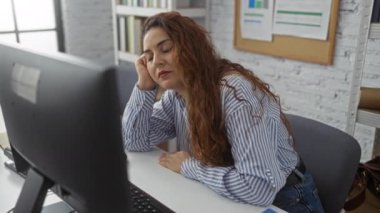 Modern ofiste uyuyan kadın yorgun ve bitkin hissediyor. Profesyonel ortamda, doğal ışık ve düzenli çalışma alanı olan yoğun bir iş günü..