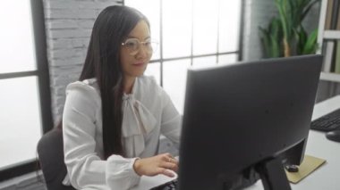 Modern ofis ortamında çalışan beyaz gömlek ve gözlüklü, parlak iç tasarım ve parlak doğal ışıklandırma ile çevrili bir kadın..