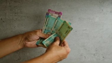 Gri beton bir arka planda Hindistan parası tutan eller