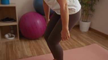 Evde egzersiz yapan, spor salonunda spor aletleriyle esneme hareketleri yapan, sağlıklı bir yaşam tarzı sergileyen, orta yaşlı, parlak bir odada yaşayan Latin bir kadın..