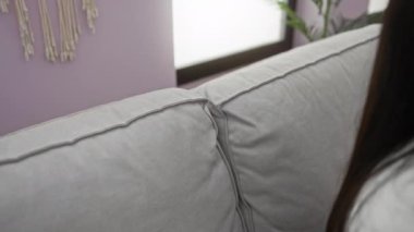 Elleri başının arkasında, rahat bir kanepede rahat bir şekilde uzanan bir kadın dairesinin rahat salonunda huzurlu ve huzurlu bir an yaşıyor..