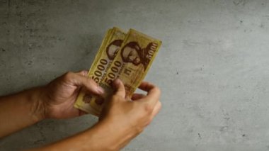 Elinde Macar banknotları tutan kişi beton bir arka planda, elinde birden fazla banknot var..