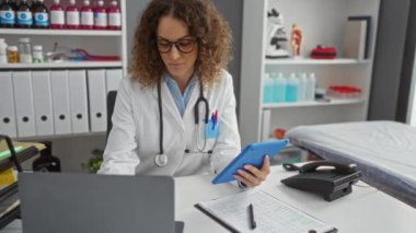 Tıbbi ekipman ve raflarla çevrili, tablet ve belgelerle çalışan beyaz önlüklü bir kadın profesyonel ve klinik atmosferi ön plana çıkarıyor..