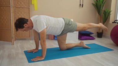 Kapalı bir kaplıcada yoga minderinde egzersiz yapan bir adam, sakin bir ortamda sağlığa ve sağlığa odaklanmış olgun bir yaşam tarzını gösteriyor..