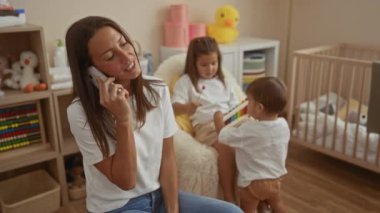 Kız ve oğlan yakınlarda oynaşırken, rahat bir yatak odasında konuşan bir kadın, oyuncaklarla ve beşiklerle dolu bir evde aile sevgisini sergiliyor..