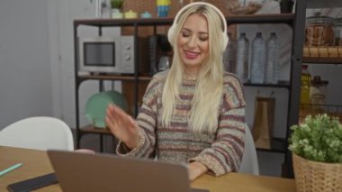 Evde kulaklıkla konuşan, rahat oturma odasında oturan, raflar ve bitkilerle çevrili, el hareketleriyle duygularını ifade eden bir kadın..