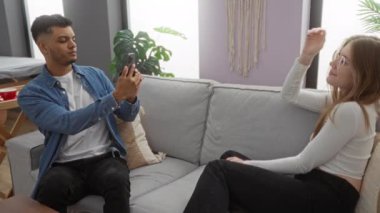 Kadın ve erkek rahat oturma odasında kanepede eğleniyor, telefonla mutlu anları yakalıyorlar..