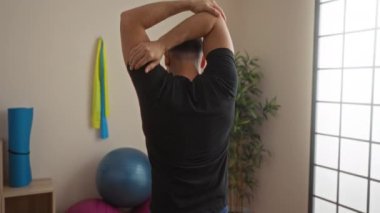 Spor salonunda kollarını uzatan bir adam, spor aletleri etrafında, kapalı bir ortamda, spor salonunda, spor salonunda ve sağlıklı bir yaşam tarzında..