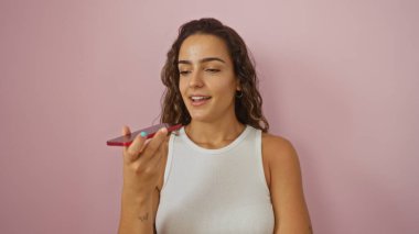 Pembe arka planda akıllı telefondan konuşan genç bir kadın izole edilmiş bir ortamda esmer bir yetişkinle güzel ve mutlu bir an yaşıyor.