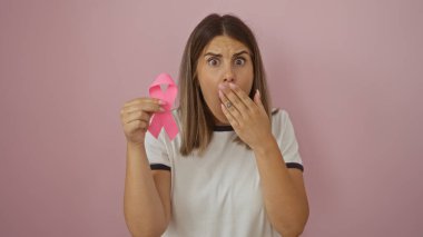 Pembe arka planda pembe kurdele tutan genç bir kadın şaşırdı, farkındalık desteği gösteriyor.