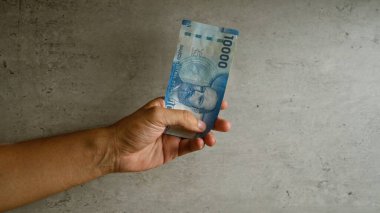 Somut bir arkaplanda el ele tutuşan Şili pezosu, 10000 peso 'luk banknot gösteriyor..