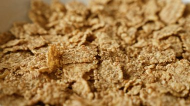 Gevrek mısır gevreğinin yakın görüntüsü kahvaltı için mükemmel, mısır gevreğinin dokusunu ve altın rengini vurguluyor.