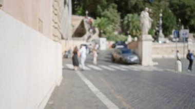 Piazza del Popolo Roma 'da bulanık bir manzara. İnsanlar ve arabalar hafif odaklı. Güneşli bir günü tarihi heykeller ve mimariyle yakalıyorlar..