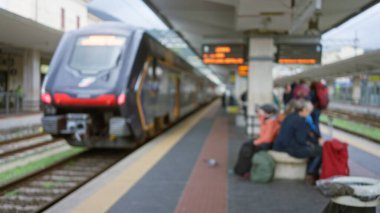 Bulanık yolcular kalabalık bir tren istasyonunda bekliyor. Yakınlarda bir bavul var, aceleci ve aceleci yolcuları yakalıyor..