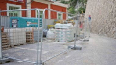 Bulanık inşaat alanı, çözünmüş ekipmanlar, bokeh bariyerleri ve odaksız bir endüstriyel atmosfer yaratan bir arka plan binası..