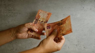 El ele tutuşup Güney Afrika rand banknotlarını somut bir arkaplanda karşılaştırarak Mandela 'nın para birimindeki imajını öne sürüyor..