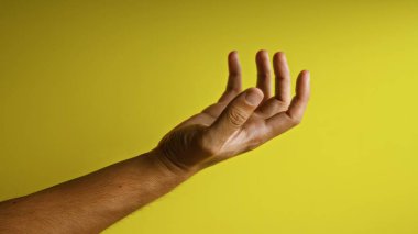 Adamın eli ve parmakları parlak sarı bir arka plana uzanıyor.
