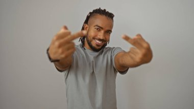 Örgülü genç adam, izole edilmiş beyaz bir arkaplanda orta parmaklarını gösteriyor. Uyumsuzluğunu ve tarzını cesur bir gülümseme ile ifade ediyor. Kişisel davranışlarını gösteriyor..