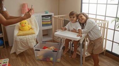 Kadın, oğlunun ve kızının sıcak yatak odasındaki sevgi dolu anlarını yakalıyor. Beşiğiyle, aile bağını ve evin içinde neşeli bir atmosferi ön plana çıkarıyor..