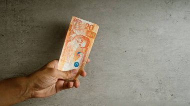 Elde tutulan Filipinli pezoları somut bir arkaplanda, yakın plan çekimleri gösteriyor ve Filipinler 'deki finansal işlemleri vurguluyor.