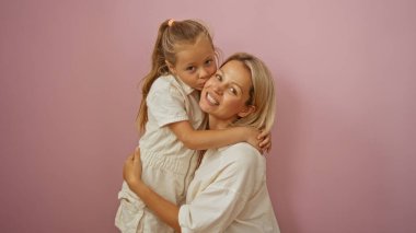 Sarışın bir kadın, pembe bir arka planda onu yanağından öpen kızını kucaklıyor. Sevgisini ve aile bağını anlatıyor..