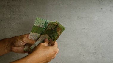 Hong Kong doları banknotları tutan adam somut arka plana karşı banknotlara ve ellere odaklanmış durumda..