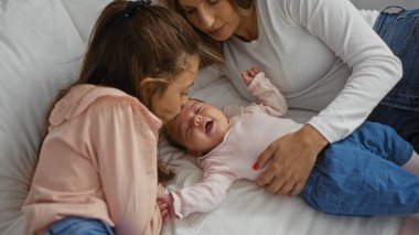 Anne ve kızı huzur içinde uyuyan küçük bir kıza sevgi ve sevgiyle bakıyor. Sıcak ve sevgi dolu huzurlu bir aile anını somutlaştırıyor..