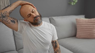 Yakışıklı, sakallı ve dövmeli bir adam. Oturma odasında boynunu içeri doğru uzatıyor.