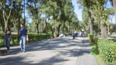 Villa borghese bahçelerinde ağaçlarla yürüyen bulanık insanlar Roma, İtalya 'da sakin bir açık hava yaratıyor. Odaklanamadığı bokeh etkisi olan huzurlu bir park sahnesini vurguluyor..