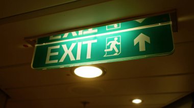 Aydınlatılmış çıkış işareti, kapalı alanda yeşil bir ok ile parlar. Bu da modern bir bina koridorunda geceleri acil durum hazırlığını etkin bir şekilde vurgular..