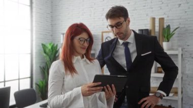 İş ortakları, bir erkek ve bir kadın, takım çalışmasını ve yenilikleri vurgulayarak, modern bir ofiste bir tabletle işbirliği yaparlar..
