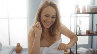 Havluya sarılı kaplıca odasında sevinçle dans eden kadın güzellik ortamında rahatlama ve mutluluk hissi taşıyor..