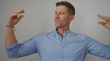 Kendine güveni tam bir adam, elleri beyaz bir arka planda, ifade edici yüz ifadeleri olan mavi bir gömlekle yakalanmış, hareketli ve konuşkan..