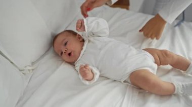 Sevimli yeni doğmuş çocuk rahat bir yatak odasında yatakta uzanıyor. Evde samimi ve hassas bir çocukluk anını yaşıyor..