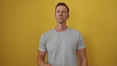 Genç adam elleri ile bir öpücük üflüyor canlı sarı bir arka plan, neşeli bir yüz ve rahat, izole bir şekilde yayılan bir stil.