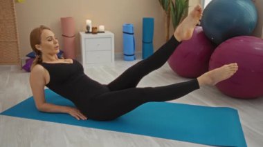 Evde yoga minderinde egzersiz yapan bir kadın spor salonunda sağlıklı bir yaşam tarzı sergiliyor..