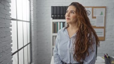 Ofiste duran kadın, kendine güvenen genç iş dünyasından profesyonel İspanyol çalışma alanından pencere ışığı altında gayri resmi olarak geçti..