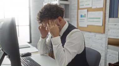 Ofis masasında bilgisayar ve evrak işleriyle boğuşan bir adam profesyonel çalışma alanında, gözlüklü ve resmi kıyafetli hayal kırıklığını gösteriyor..