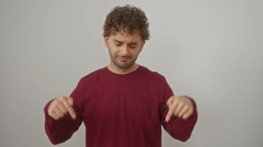 Genç İspanyol adam tişört giymiş, üzgün bir ifadeyle işaret ediyor, mutsuz ve üzgün, yönü gösteriyor, izole edilmiş beyaz arka plan yüzünden depresyonda.